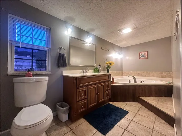 a bathroom with a granite countertop toilet sink and mirror