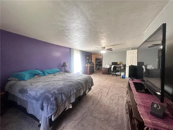 a spacious bedroom with a bed and a flat screen tv