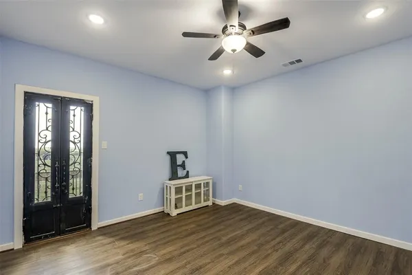 an empty room with wooden floor chandelier fan and windows