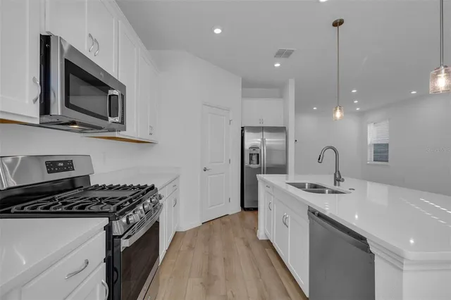 a kitchen with stainless steel appliances granite countertop a sink stove and wooden floor