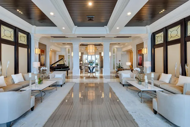 a living room with furniture large windows wooden floor and a chandelier