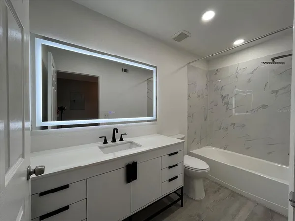 a bathroom with a double vanity sink toilet mirror and bathtub
