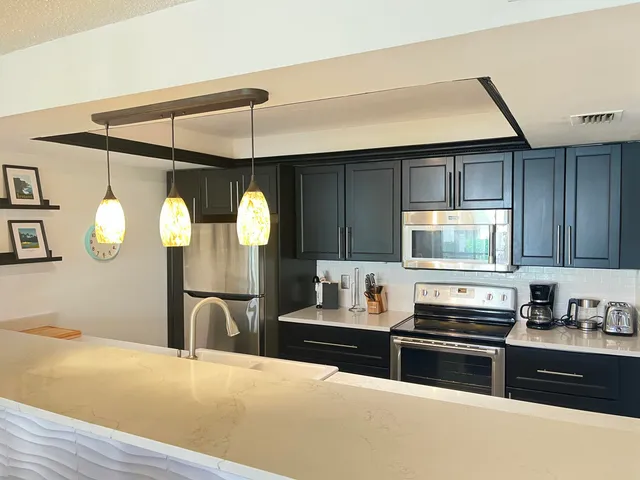 a kitchen with stainless steel appliances granite countertop a stove a sink and a microwave