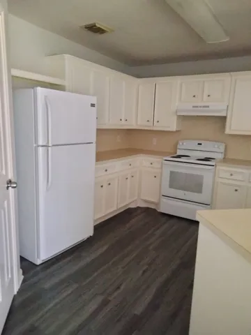 a kitchen with cabinets stainless steel appliances and wooden floor