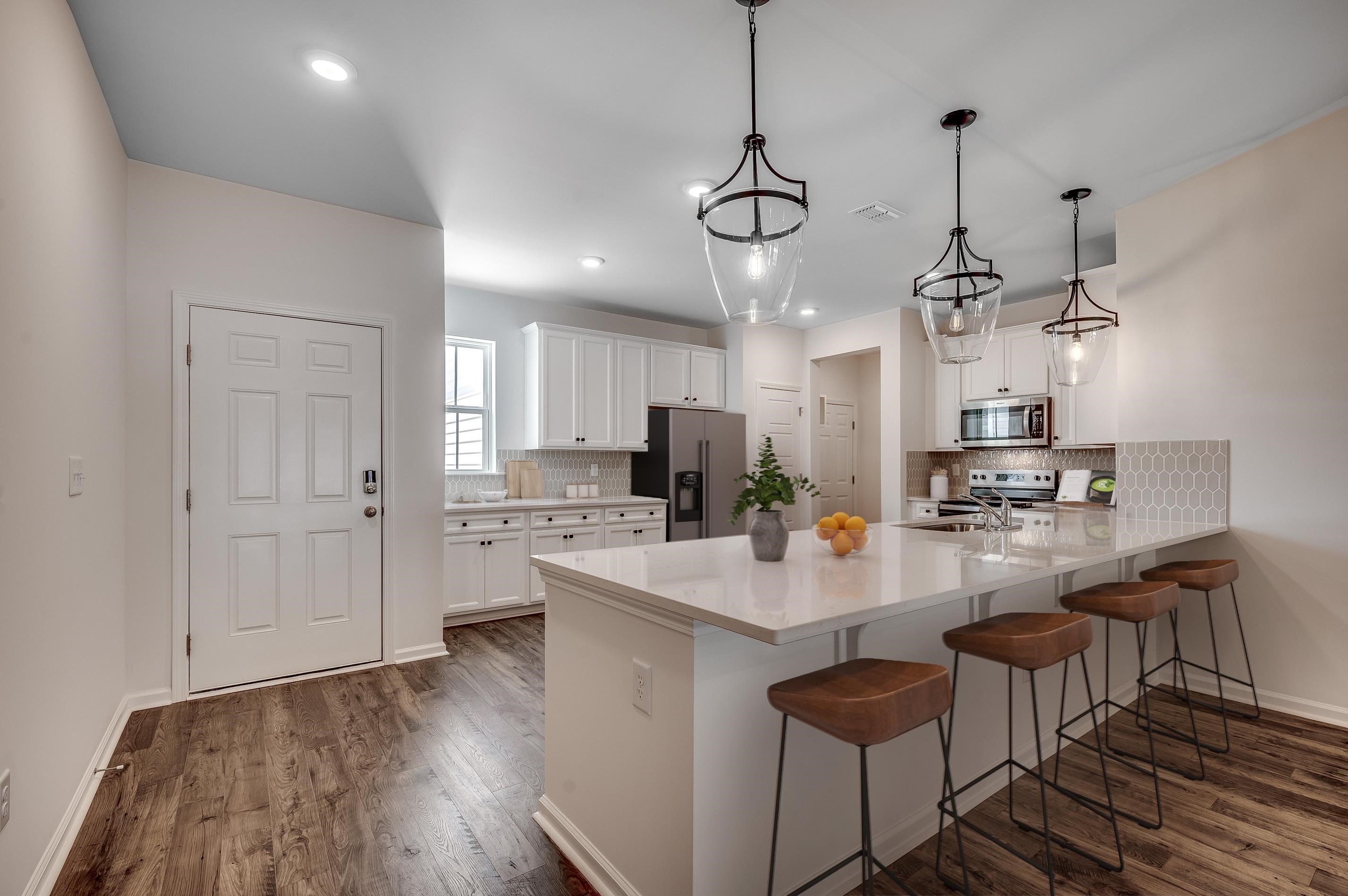 359 Kapalua Loop Little River, SC 29566 - Photo 2 of 13 Kitchen with a kitchen bar, appliances with stainless steel finishes, white cabinets, a peninsula, and tasteful backsplash