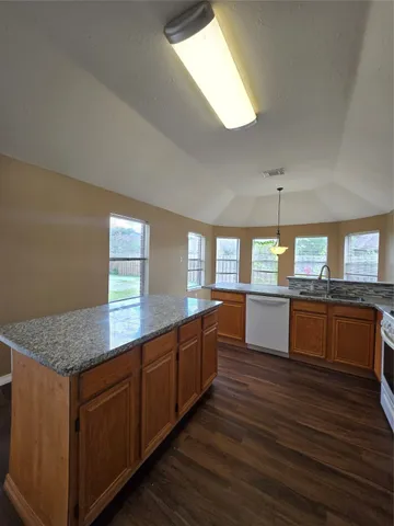 a kitchen with stainless steel appliances granite countertop wooden cabinets and a wooden floor
