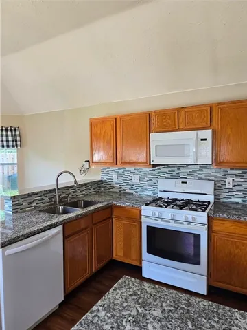 a kitchen with stainless steel appliances granite countertop a stove a sink and a microwave