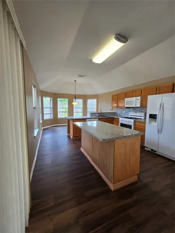 a living room with couches and kitchen view with wooden floor