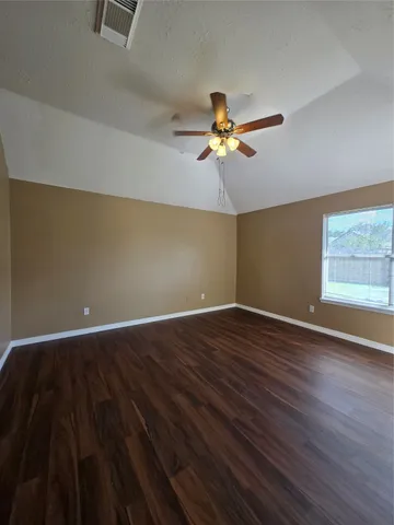 a view of an empty room with a window and wooden floor