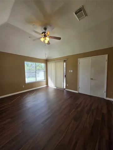 a view of an empty room with a window and wooden floor