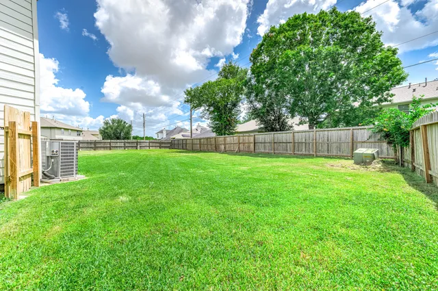 a view of a yard with a large tree and wooden fence