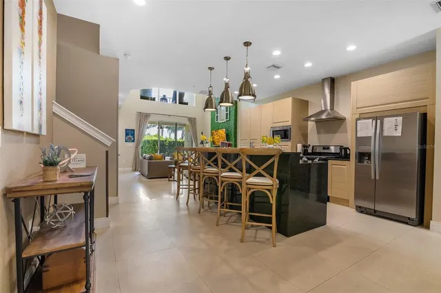 a kitchen with stainless steel appliances kitchen island granite countertop a refrigerator a sink a stove and a dining table with wooden floor