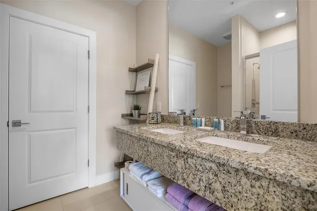 a bathroom with a granite countertop double vanity sink and a mirror