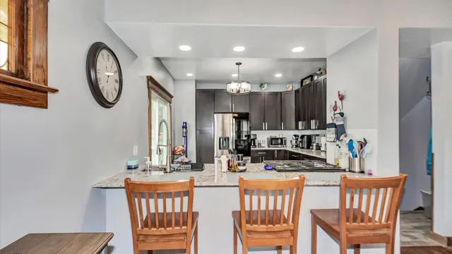 a kitchen with stainless steel appliances granite countertop a dining table chairs and a refrigerator