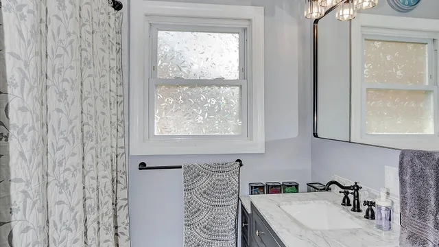 a bathroom with a granite countertop sink a window and a shower