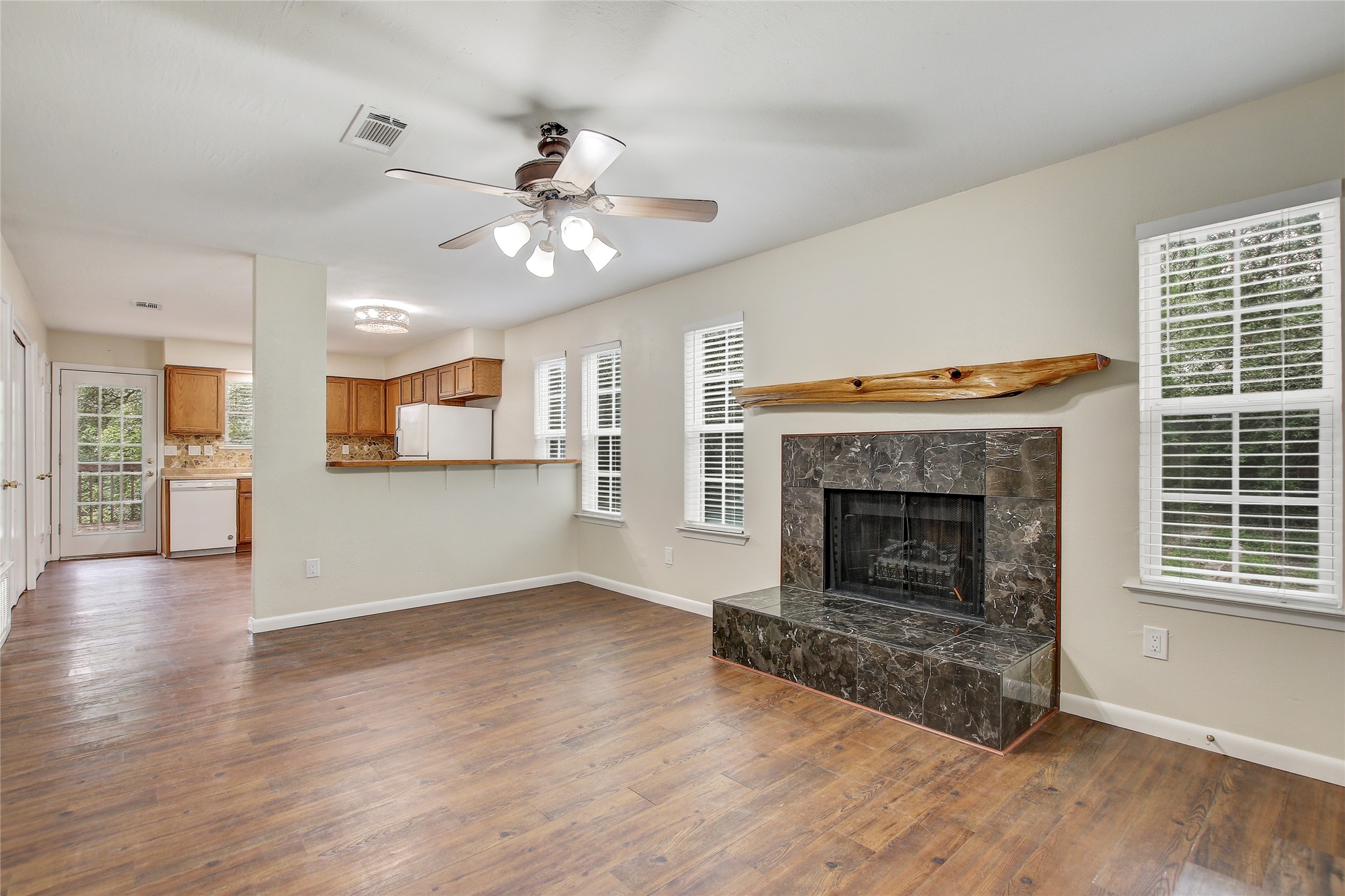 6902 Rifle Bend, Unit B Austin, TX 78736 - Photo 2 of 34 a view of a livingroom with a fireplace a ceiling fan and kitchen view