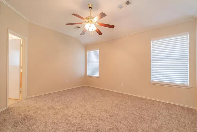 an empty room with chandelier fan and windows