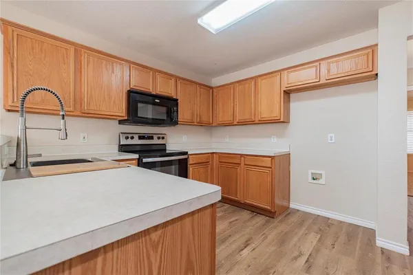 a kitchen with granite countertop wooden cabinets a stove top oven a sink and dishwasher
