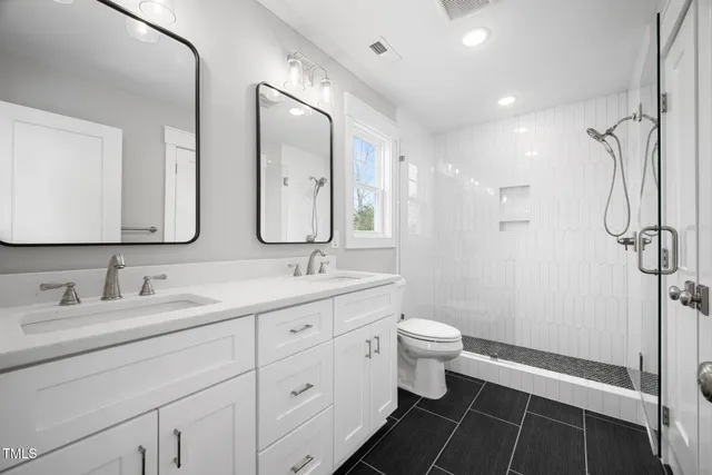 a bathroom with a double vanity sink toilet and shower