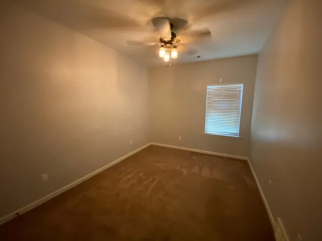 en empty room with windows and chandelier fan