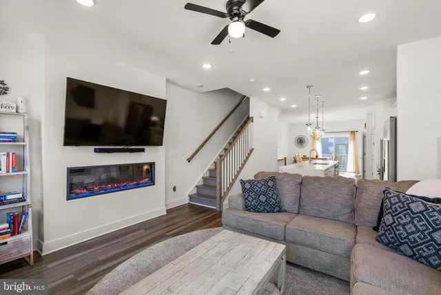 a kitchen with stainless steel appliances a refrigerator a stove a sink a dining table and chairs with wooden floor