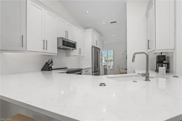 a large white kitchen with sink and a refrigerator