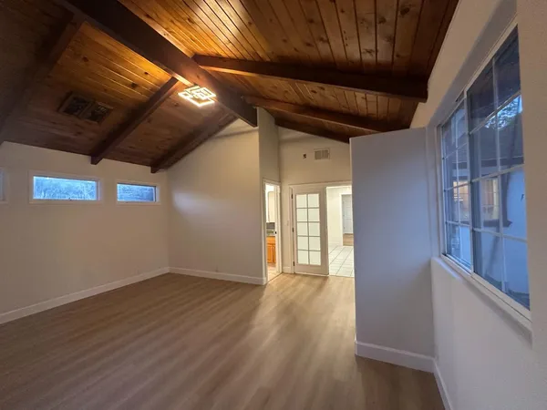 a view of an empty room with wooden floor and a window
