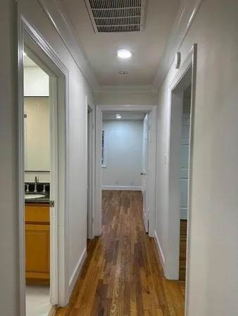 a view of a hallway with wooden floor and a bathroom