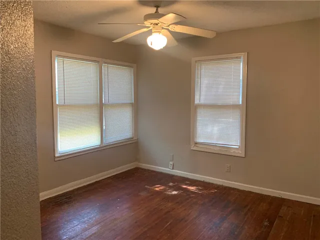 an empty room with wooden floor closet and windows