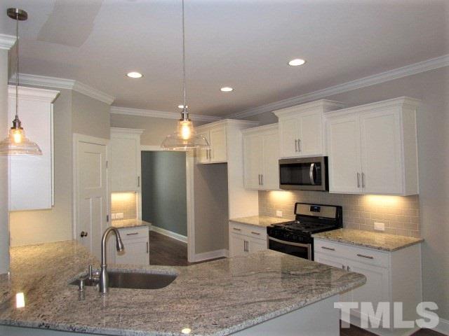 1628 Forest Road Wake Forest, NC 27587 - Photo 5 of 25 Beautiful kitchen w/ white painted cabinets w/ soft close on doors & drawers, under cabinet lights, tile backsplash, hardwoods floors, single bowl sink, MOEN faucet, SS appliance package, recessed lights, large pantry.