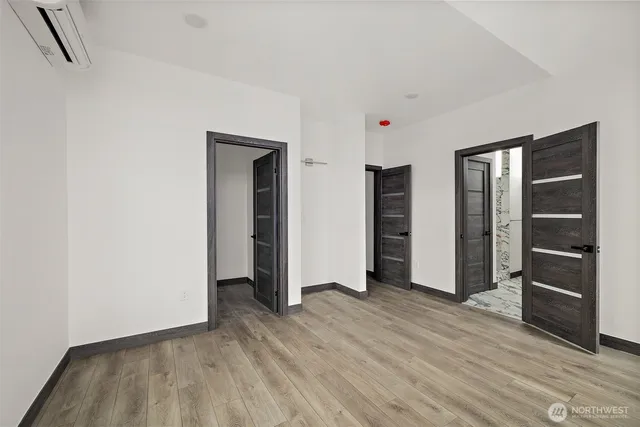 a view of an empty room with wooden floor and closet