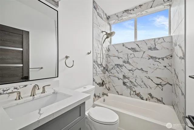 a bathroom with a bathtub shower sink vanity mirror and toilet