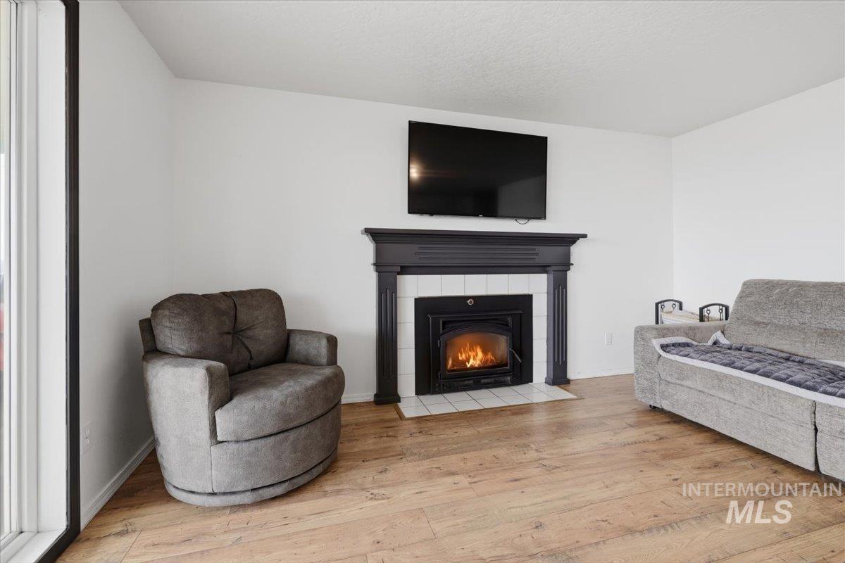 24440 Kenridge Road Caldwell, ID 83607 - Photo 22 of 48 Living area featuring a traditional fireplace with a dark wood mantel and white tile surround, wood-finish flooring, and white painted walls
