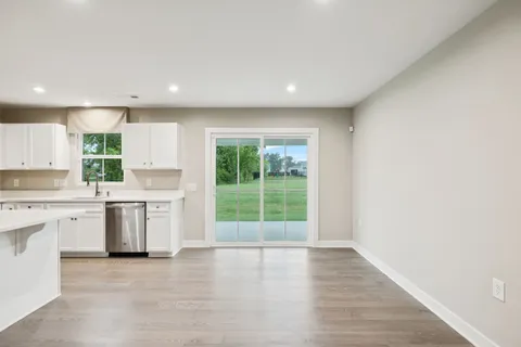 a view of a kitchen with a sink and dishwasher a stove top oven with wooden floor
