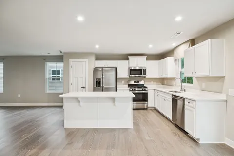a kitchen with stainless steel appliances a white cabinets and wooden floor