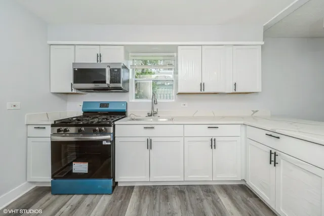 a kitchen with cabinets stainless steel appliances and wooden floor