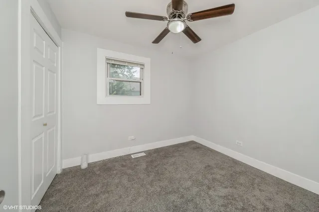 an empty room with a window and a fan