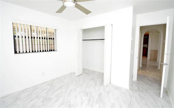 an empty room with wooden floor chandelier fan and windows