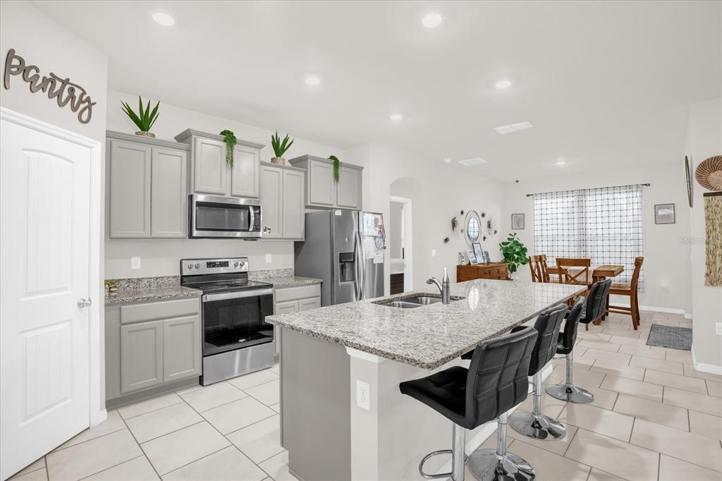 6775 Sarus Crane Point Harmony, FL 34773 - Photo 4 of 28 a kitchen with stainless steel appliances a stove a sink a microwave a dining table and chairs