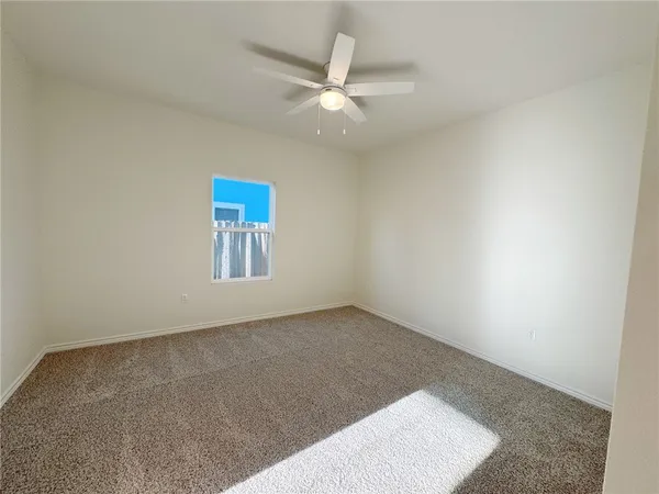 en empty room with windows and ceiling fan