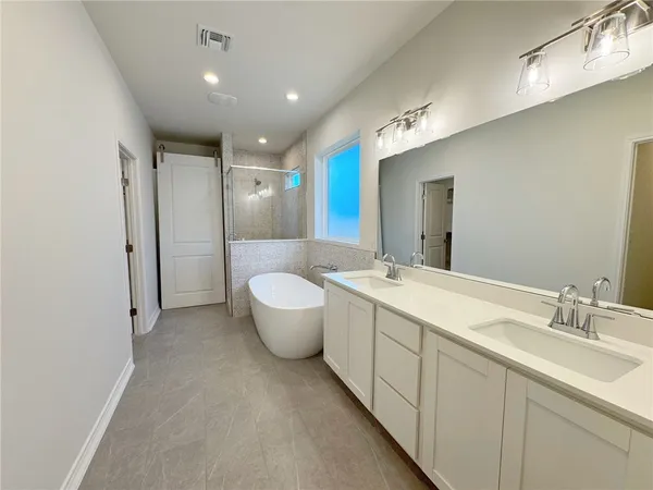 a bathroom with a double vanity sink mirror and bathtub