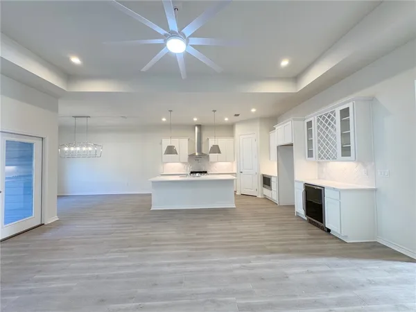 a view of kitchen with kitchen island a sink wooden floor and a living room