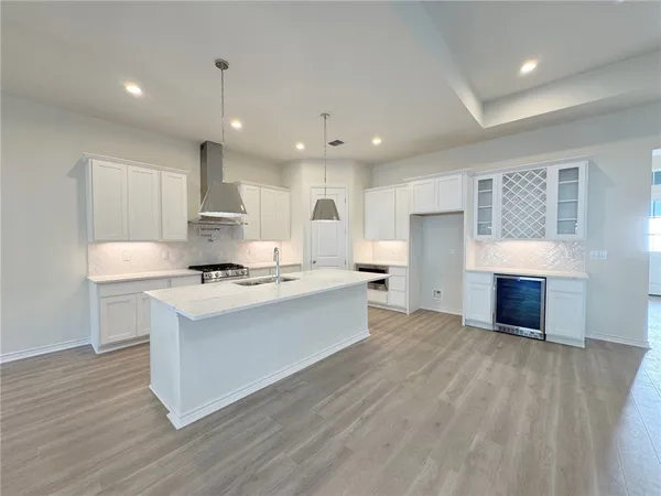 a large kitchen with kitchen island a sink wooden floor and a counter top space