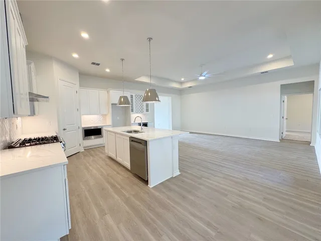 a large white kitchen with a stove a sink dishwasher and a refrigerator with wooden floor