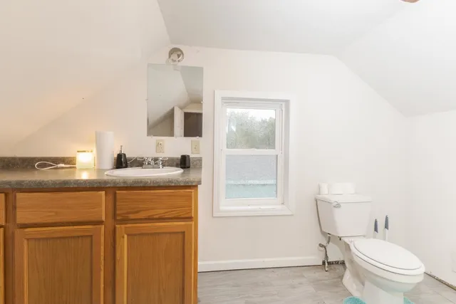 a bathroom with a granite countertop sink mirror vanity and toilet