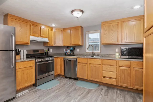 a kitchen with stainless steel appliances granite countertop a stove a sink and white cabinets
