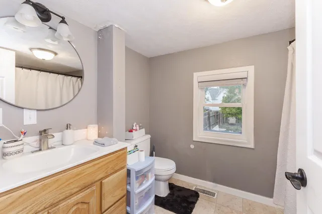 a bathroom with a toilet a sink a mirror a vanity and window