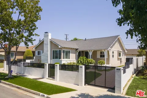 a front view of a house with a garden and plants