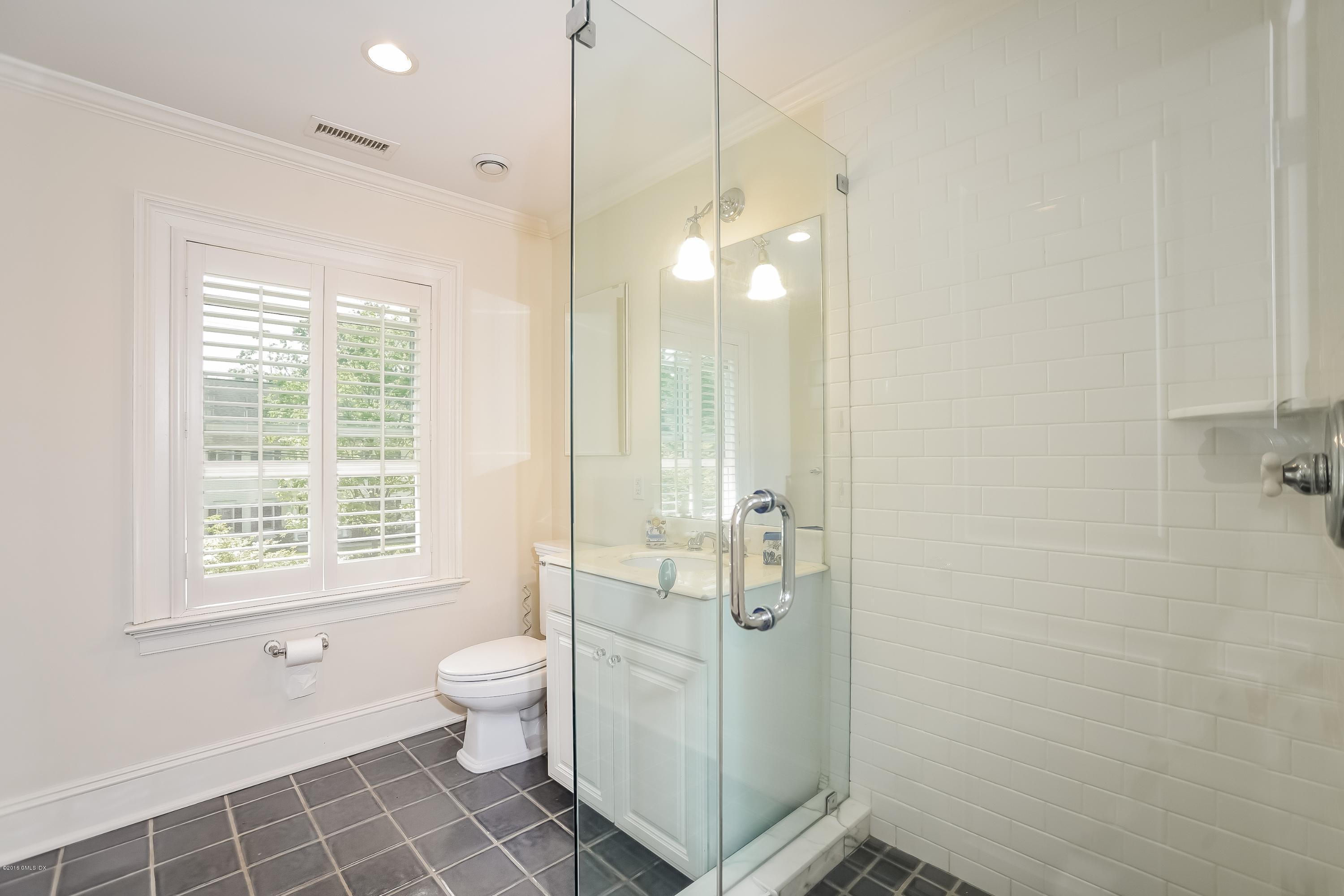 35 Lockwood Road Riverside, CT 06878 - Photo 27 of 39 a bathroom with a granite countertop toilet a sink a shower and a window