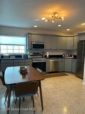 a kitchen with stainless steel appliances granite countertop a stove a refrigerator a sink a dining table and chairs
